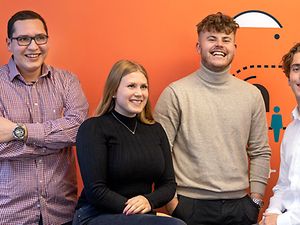 Karriere: Eine junge Frau, die lächelnd vor ihrem Laptop sitzt